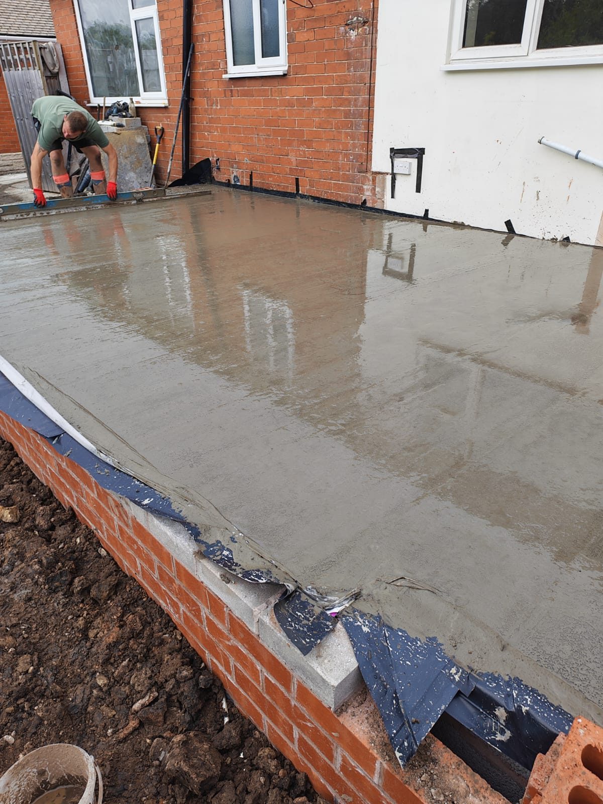 Wet concrete slab laid over the damp proof membrane on a new brick and block base